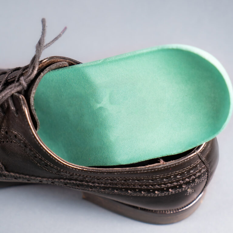 Semelle orthopédique insérée dans une chaussure, illustrant l'importance des dispositifs médicaux adaptés