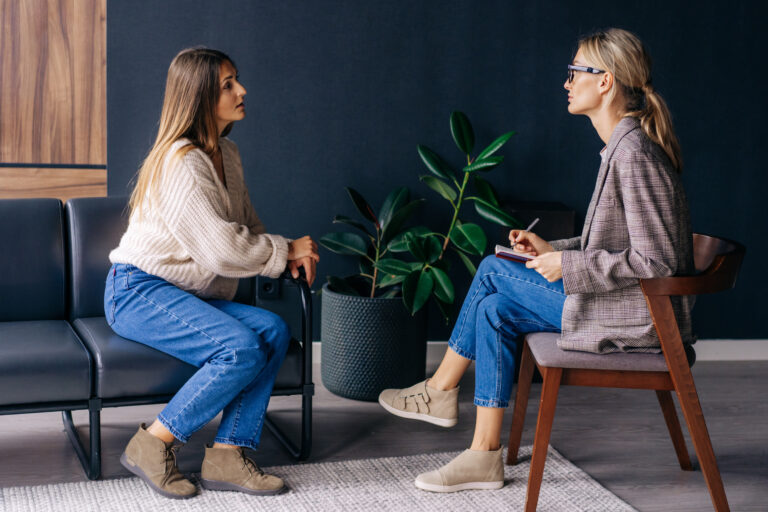Une jeune femme échange avec un psychologue lors d’un entretien dans un cadre professionnel.