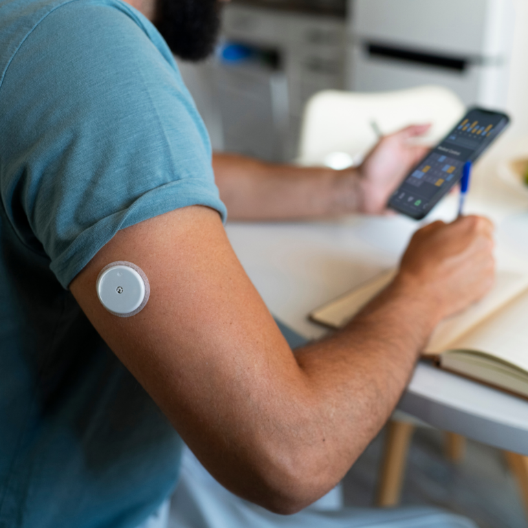 Personne utilisant un capteur de glycémie connecté sur le bras pour surveiller son diabète, un facteur de risque de l’insuffisance cardiaque.