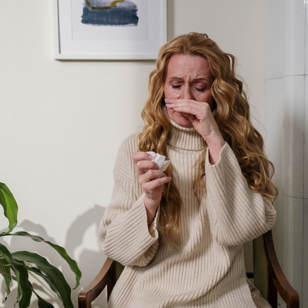 Femme présentant des symptômes d'allergie au pollen avec les yeux larmoyants, le nez irrité et un mouchoir à la main.
