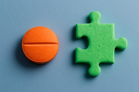 dangers-auto-medicamentation-mutuelle-smatis Deux comprimés colorés sur fond bleu, dont un en forme de pièce de puzzle, illustrant les dangers d'une automédication inadaptée
