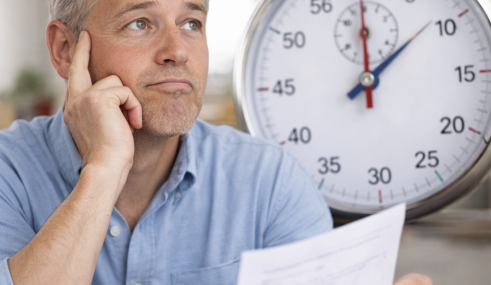 Homme quinquagénaire pensif tenant un document de santé devant un grand chronomètre illustrant le délai de remboursement