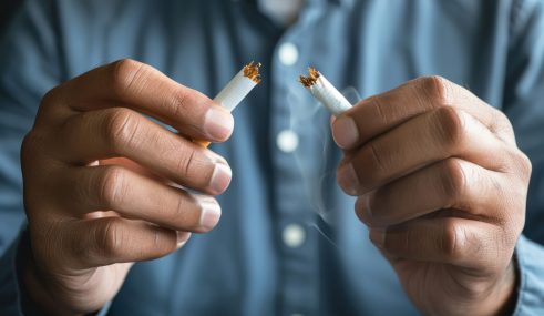 Homme cassant une cigarette en deux, symbolisant le sevrage tabagique et l’arrêt du tabac Homme cassant une cigarette en deux, symbolisant le sevrage tabagique et l'arrêt du tabac